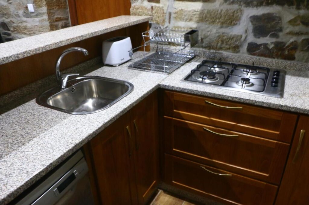 Cozinha da Casa do Poço, equipada com placa, torradeira, maquina de café, máquina de lavar a loiça, microondas e frigorífico combinado